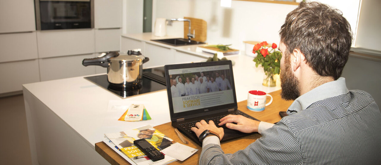 Man working on his laptop at the kitchen table